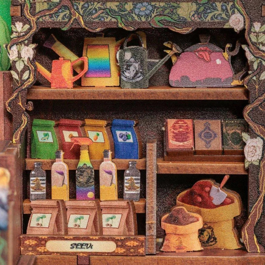 Miniature shelf with colorful teapots, bottles, and seed packets for model kits and collectibles.