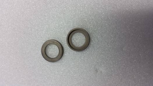 Two gray metal washers on textured surface, model kit hardware parts