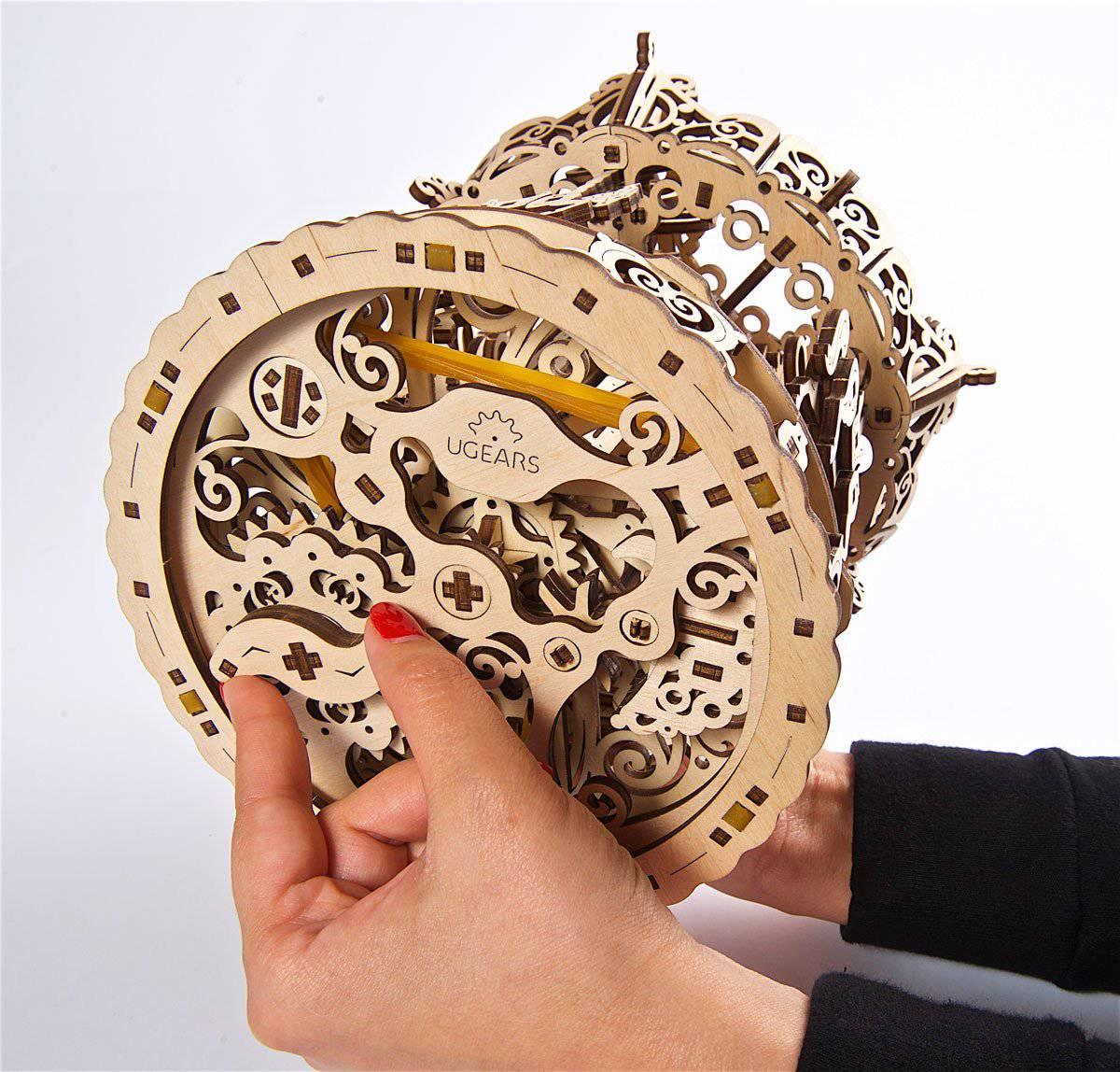 UGears wooden mechanical model kit with intricate gears and laser-cut details, held in hands