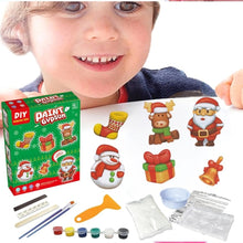 Child holding a paint gypsum's kit with Christmas-themed decorations and supplies.